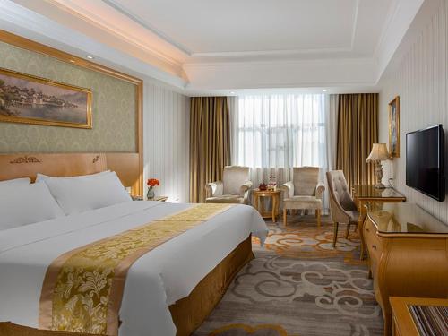 a hotel room with a large bed and a television at Vienna Hotel Meizhou Jiangnan in Meizhou