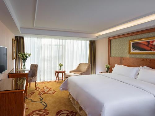 a hotel room with a large bed and a large window at Vienna Hotel Mix City in Shenzhen