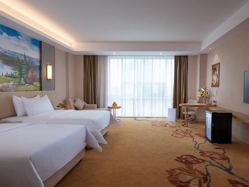 a large hotel room with two beds and a television at Vienna International Hotel (Guangdong Yunfu Emerging New City Plaza Store) in Dongkou
