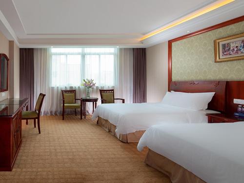 a hotel room with two beds and a table and chairs at Vienna Hotel Dongguan Songshan Lake in Dongguan