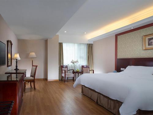 a hotel room with a bed and a table and chairs at Vienna International Hotel Yangshuo West Street in Yangshuo