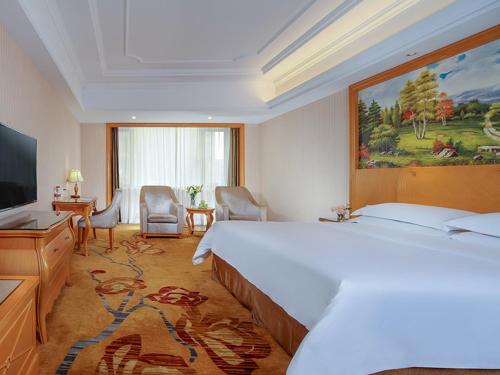 a hotel room with a large bed and a television at Vienna Hotel Chengdu Wenjiang Zhujiang Plaza in Wenjiang