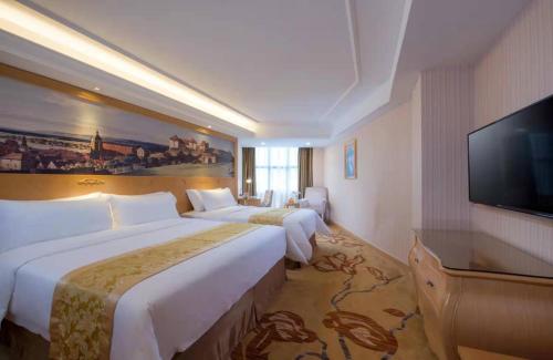 a hotel room with two beds and a flat screen tv at Vienna Hotel Meizhou Xingning District Plaza in Libei