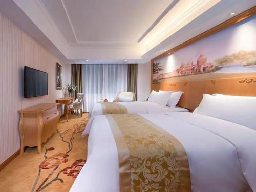 a hotel room with two beds and a television at Vienna Hotel Guangdong Zhongshan Tanzhou in Zhongshan