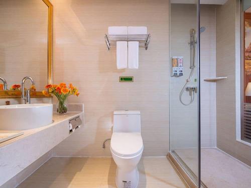 a bathroom with a toilet and a sink and a shower at Vienna International Hotel Foshan Qiandeng Lake in Foshan