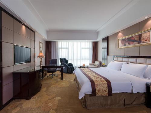 a hotel room with a large bed and a television at Vienna International Hotel Guangdong Zhongshanbei Station in Zhongshan