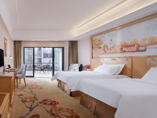 Vienna Hotel Guangzhou Panyu Huanan Country Garden في قوانغتشو: غرفة فندقية بسريرين ولوحة كبيرة على الحائط