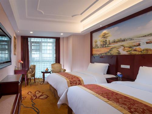 a hotel room with two beds and a painting on the wall at Vienna Hotel Shenzhen Exhibitian Center 2nd in Shenzhen