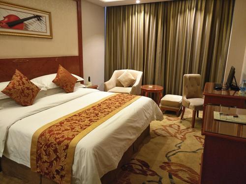 a hotel room with a large bed and a chair at Vienna Classic Hotel Kongtong Avenue in Pingliang