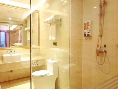 uma casa de banho com um chuveiro, um WC e um lavatório. em Vienna International Hotel Yantai Changjiang Road Xingyi Square Branch em Yantai