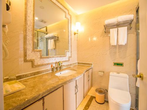 uma casa de banho com um lavatório, um WC e um espelho. em Vienna International Hotel Qinghai Xining Tianjun Bridge em Xining
