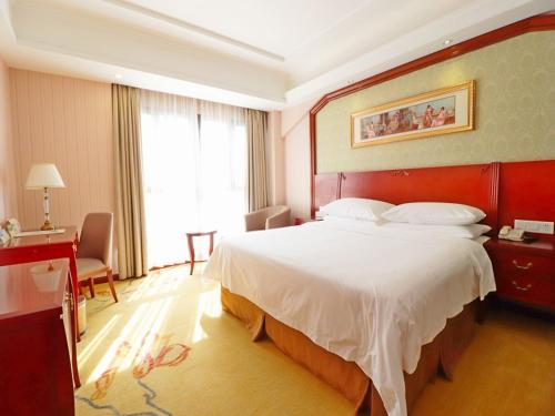 una camera d'albergo con un grande letto e una finestra di Vienna Hotel Shanghai Hongqiao National Convention Centre a Shanghai
