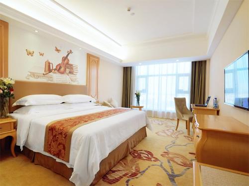 a hotel room with a large bed and a flat screen tv at Vienna Hotel Hunan Yongzhou Lengshuitan District Government Square in Guzhuting