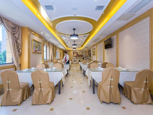 a dining room with tables and chairs and a man standing in it at Vienna Hotel Wuhan Panlong City in Wuhan