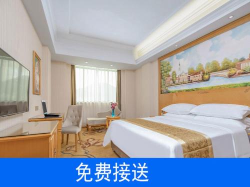 広州市にあるVienna Hotel Guangzhou South Railway Stationの大きなベッドとデスクが備わるホテルルームです。