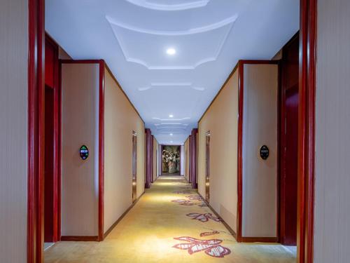 an empty hallway with a long corridor with red doors at Vienna International Hotel Jingdezheng People Square in Jingdezhen