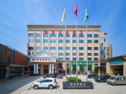 a large building with three flags on top of it at Vienna Hotel Wuhan Panlong City in Wuhan