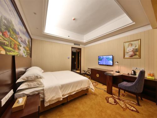 a bedroom with a bed and a desk and a television at Vienna International Hotel Zhangjiajie Tianmen Mountain in Zhangjiajie