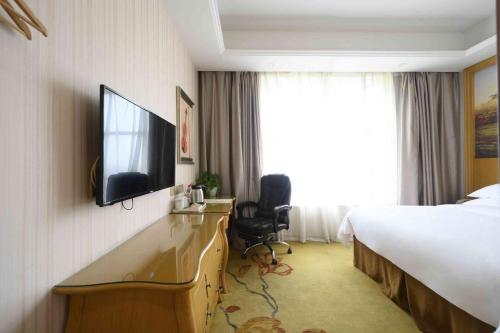 a hotel room with a bed and a flat screen tv at Vienna International Hotel Shanghai Malu Station in Jiading