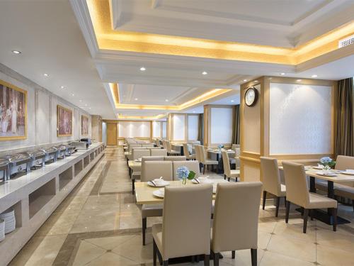a dining room with tables and chairs and a clock at Vienna Hotel Guangxi Nanjing Nanhu Park in Nanning