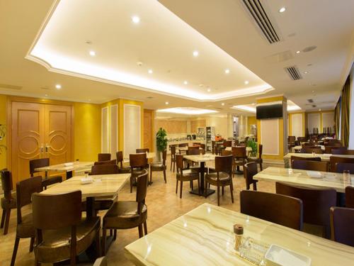 un comedor con mesas y sillas en un restaurante en Vienna International Hotel Changsha Hongxing en Changsha