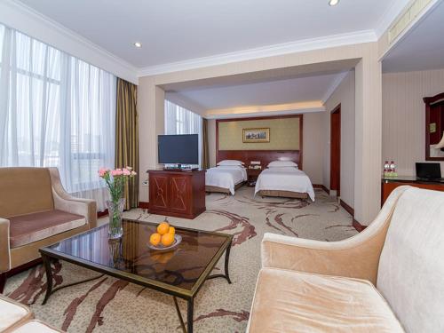Habitación de hotel con 2 camas y sala de estar. en Vienna International Hotel Xiangyang Railway Station, en Xiangyang