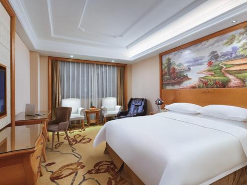 um quarto de hotel com uma grande cama branca e uma secretária em Vienna International Hotel Nanjing South Railway Station em Nanquim