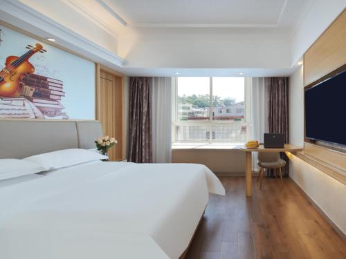 a hotel room with a large bed and a large window at Vienna International Hotel Jingdezheng People Square in Jingdezhen