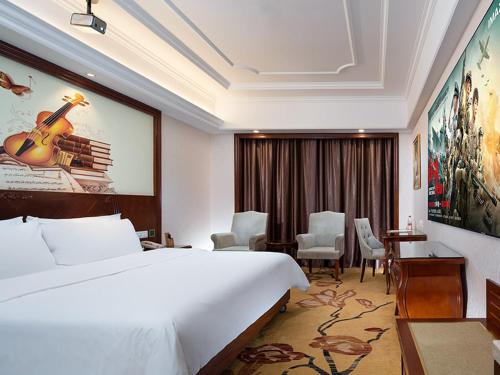Gaozhou的住宿－維也納酒店廣東高州城東客運站店，酒店客房设有一张大床和一张书桌。