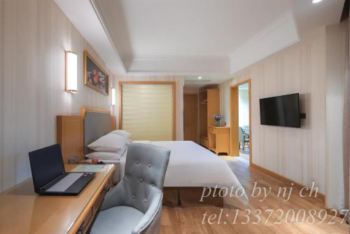 a bedroom with a bed and a desk with a laptop at Vienna 3 good hotel (Anhui Ningguo store) in Ningguo