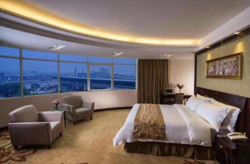 a hotel room with a bed and chairs and windows at Vienna Hotel Dongguan Houjie Exhibition Center in Dongguan