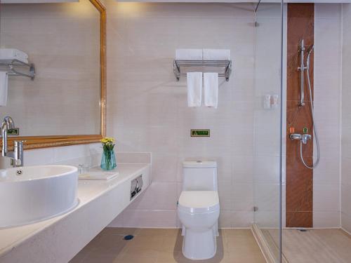 a bathroom with a toilet and a sink and a shower at Vienna Hotel Dongguan Hou Avenue Jinzuo in Hetian