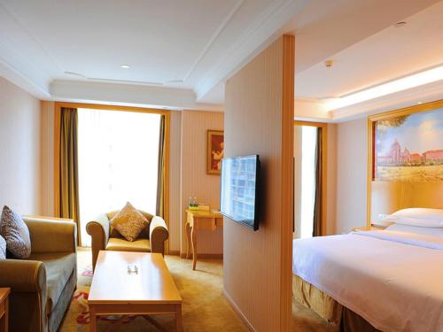 une chambre d'hôtel avec un lit et un canapé dans l'établissement Vienna Hotel Hubei Tianmen Donghu International, à Tianmen
