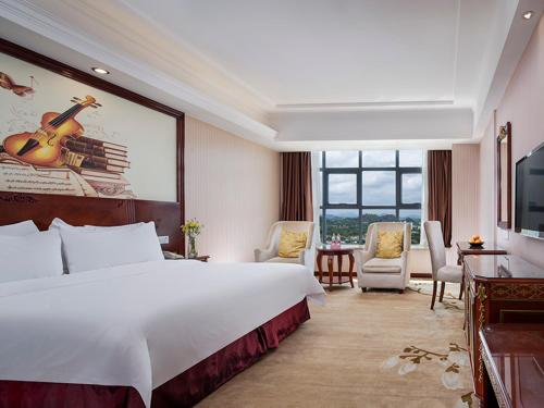 a hotel room with a large bed and a large window at Vienna Hotel Shenzhen Pingshan Shenshan Road in Longgang