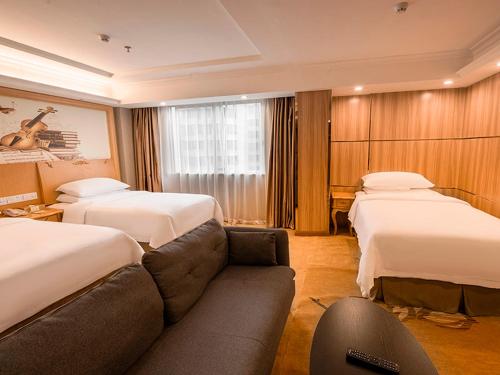 a hotel room with two beds and a couch at Vienna 3 Best Hotel(Guangdong Yangchun Bus Station Shop ) in Yangjiang