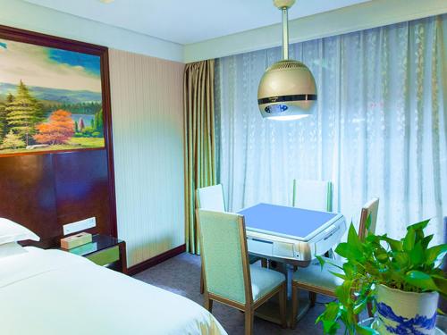 a hotel room with a table and a bed at Vienna International Hotel Zhangjiajie Tianmen Mountain in Zhangjiajie