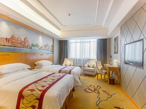 a hotel room with two beds and a television at Vienna International Hotel Haikou West Bus Station in Haikou