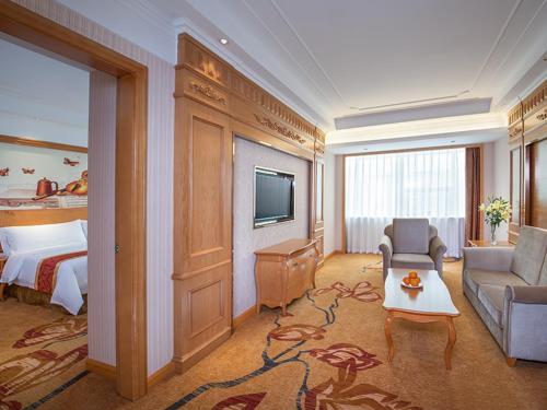 a hotel room with a bed and a couch and a television at Venus International Hotel Shenzhen Gongming Tianhong in Xitian