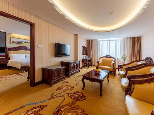 a hotel room with a bed and a living room at Vienna Hotel Jingxi Zhongshan Park in Jingxi