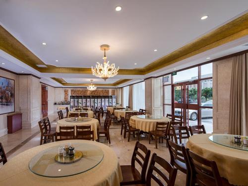 a restaurant with tables and chairs and a chandelier at Vienna International Hotel Inner Mongolia Alxa League in Alxa Left