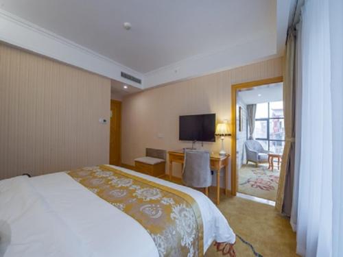 Habitación de hotel con cama, escritorio y TV. en Vienna 3 Best Hotel Liuzhou Yuejiang Road en Sanjiang