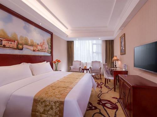Vienna Hotel Shenzhen Bao'an Xin'an في باوان: غرفة فندقية بسرير كبير وتلفزيون بشاشة مسطحة