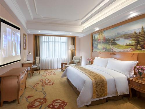 una camera d'albergo con un grande letto e una scrivania di Vienna Hotel Guangzhou Tianhe Bus Station a Canton
