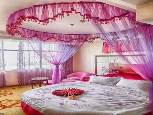 Un dormitorio rosa con una cama grande con flores. en Vienna Hotel Wuxi Wangzhuang Road, en Wuxi