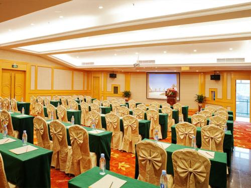 a banquet hall with green tables and chairs and a screen at Vienna International Hotel Shenzhen Dameisha in Shenzhen