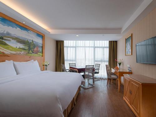 a hotel room with a large white bed and a desk at Vienna Hotel(Fuzhou Changle International Airport) in Fuzhou