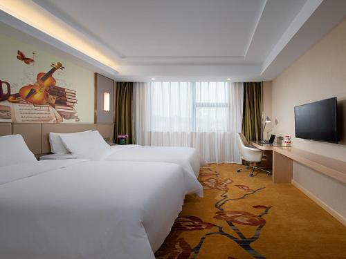 a hotel room with two beds and a flat screen tv at Vienna Hotel(Ganzhou Railway Station Shop) in Ganzhou
