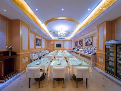 a large dining room with tables and white chairs at Vienna Hotel Whhan xingye road stone bridge subway station store in Wuhan