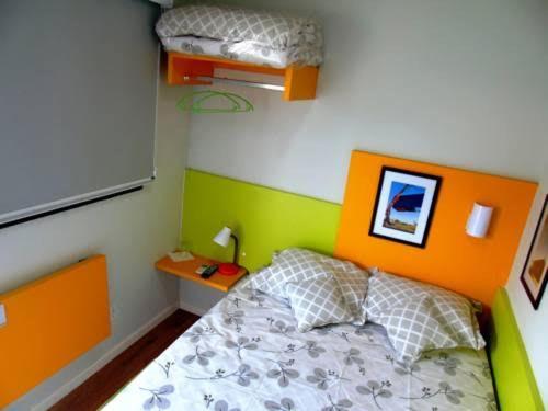 トレス・ラゴアスにあるEcobox Hotelのベッドルーム1室(オレンジと緑のヘッドボード付きのベッド1台付)