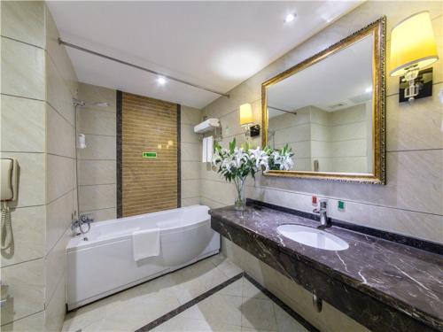 Un baño con bañera, lavabo y espejo. en Vienna Hotel Guilin Exposition Center, en Guilin